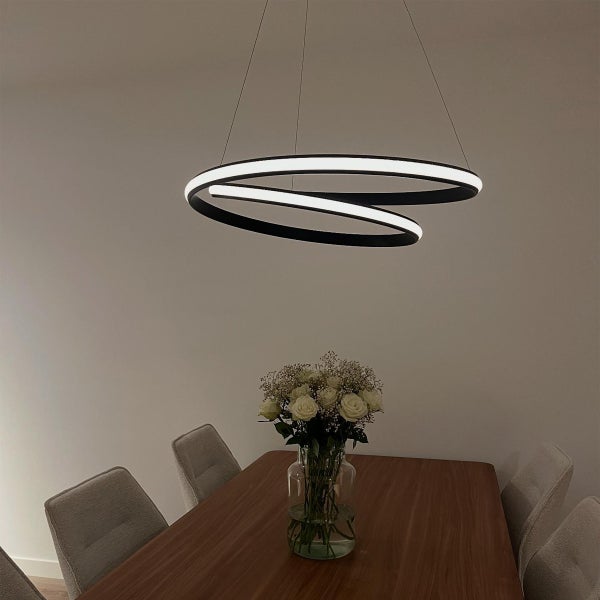 Moderne Esszimmerszene mit einem Esstisch aus Holz, Stühlen und einer spiralförmigen LED-Hängeleuchte.