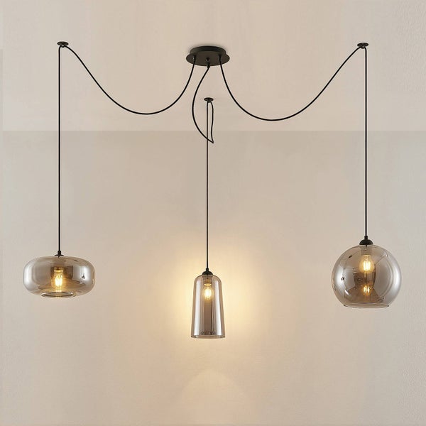 Dreiflammige Pendelleuchte mit rauchgrauen Glasschirmen in verschiedenen Formen und schwarzen Kabeln.
