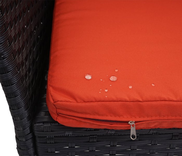 Wasserabweisendes orangefarbenes Sitzkissen auf einem Gartenstuhl aus dunklem Polyrattan mit Reißverschluss und Wassertropfen auf dem Stoff.