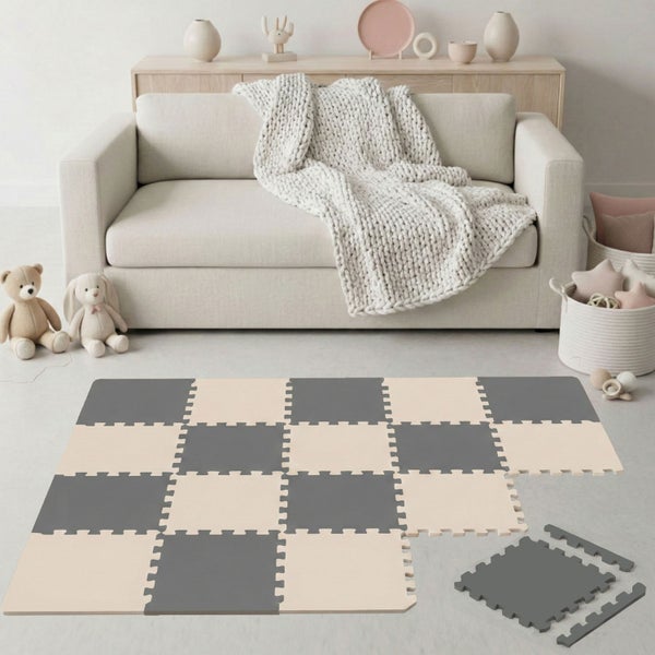 Schaumstoff-Puzzlematte mit Schachbrettmuster in Grau und Beige in einem hellen, aufgeräumten Wohnzimmer mit Sofa, Strickdecke und Spielzeug.