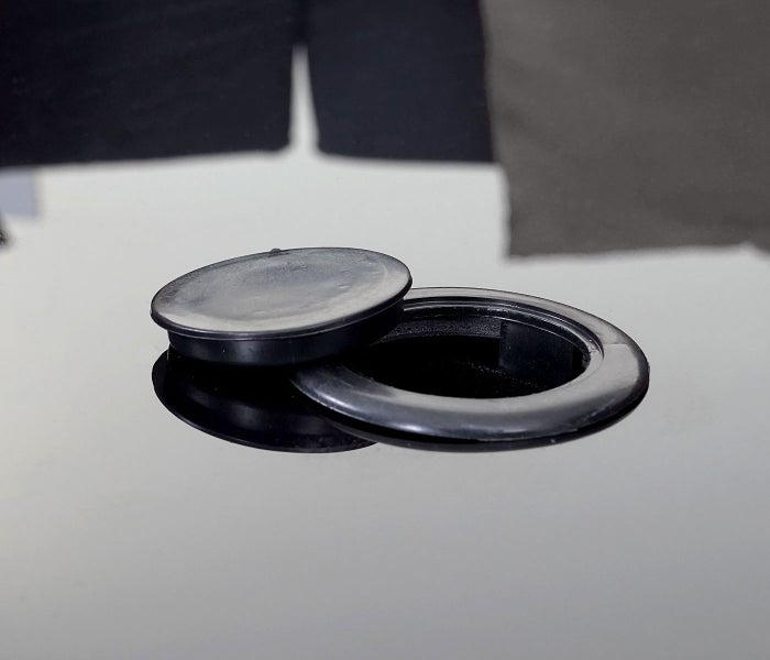 Schwarze Kabeldurchführung aus Kunststoff für den Schreibtisch mit abnehmbarem Deckel.