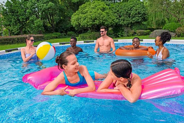 Menschen in einem großen Aufstellpool im Garten mit Luftmatratze, Schwimmring und Wasserball.