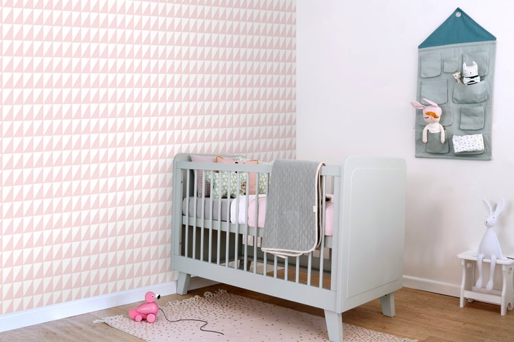 Kinderzimmer mit Kinderbett, Wandtapete mit Dreiecksmuster und Stoff-Wandorganizer