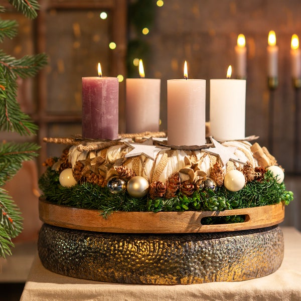 Adventskranz mit Kerzen, Tannenzweigen, Sternen und Kugeln auf einem Holzteller
