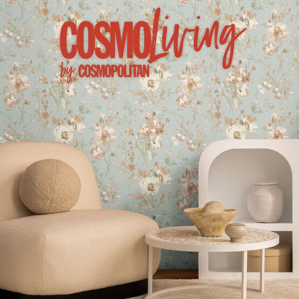 Wohnraum mit CosmoLiving by Cosmopolitan Logo und Tapete mit Blumenmuster an der Wand, dazu ein moderner Sessel und ein Beistelltisch.