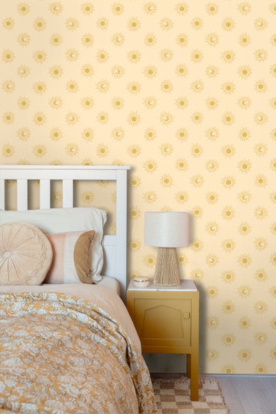 Schlafzimmer mit Bett, Nachttisch und Tapete mit Sonne- und Mondmotiven