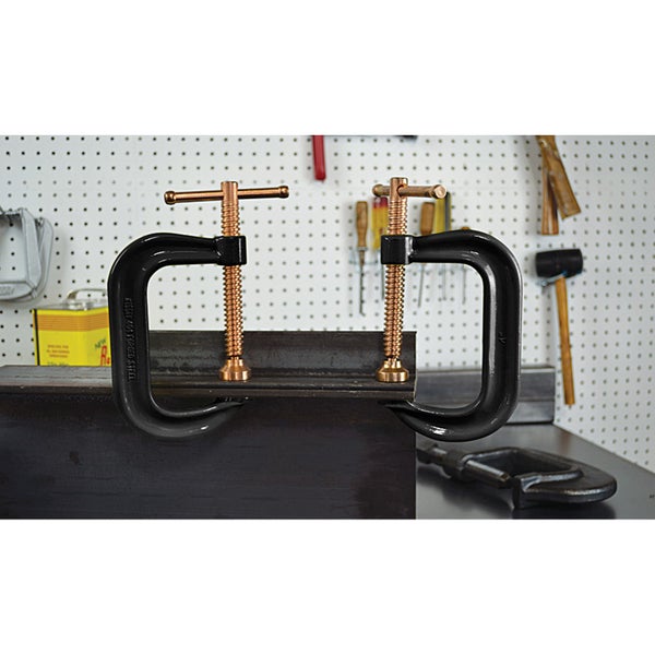 Zwei Schraubzwingen aus Stahl, die ein Metallstück fixieren.