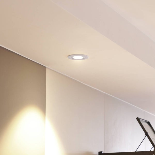 Runder LED Einbaustrahler in einer hellen Zimmerdecke montiert und eingeschaltet.