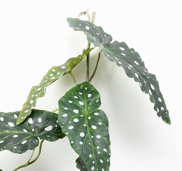 Künstliche Palme mit grünen Blättern in einem schwarzen Topf.