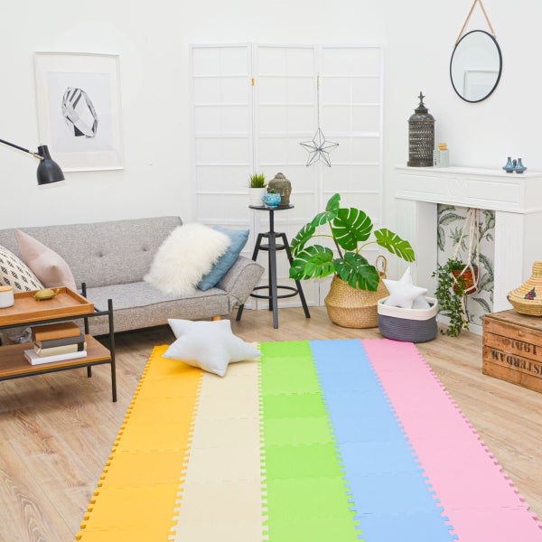 Bunte Schaumstoffmatte als Spielteppich in einem modern eingerichteten Wohnzimmer mit Sofa Pflanzen und Kaminattrappe