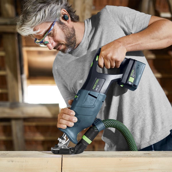 Ein Arbeiter verwendet einen Bohrhammer mit Staubabsaugung auf einer Baustelle.