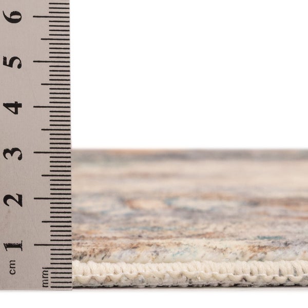 Nahaufnahme eines gemusterten Teppichs mit einem Metalllineal zur Messung der Florhöhe von circa 1 Zentimeter.