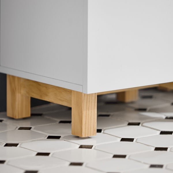 Detailansicht eines Badezimmerschranks mit Holzfüßen auf einem Boden mit sechseckigen Fliesen.