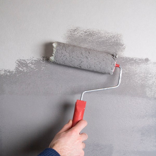 Eine Person streicht eine Wand mit einer Farbwalze.