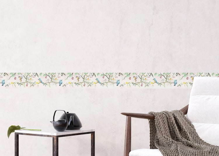 Selbstklebende Tapetenbordüre mit Vogel- und Zweigmuster an einer Wand in einem hellen Wohnzimmer.