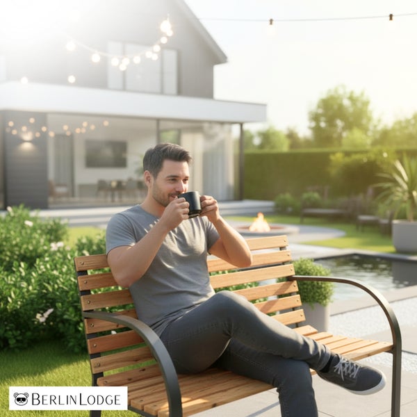 Ein Mann sitzt auf einer Gartenbank aus Holz und Metall in einem modernen Garten mit Haus und Außenbeleuchtung. Berlin Lodge Logo.