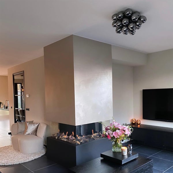 Wohnzimmer mit Kamin, Sessel, Couchtisch und Fernseher.