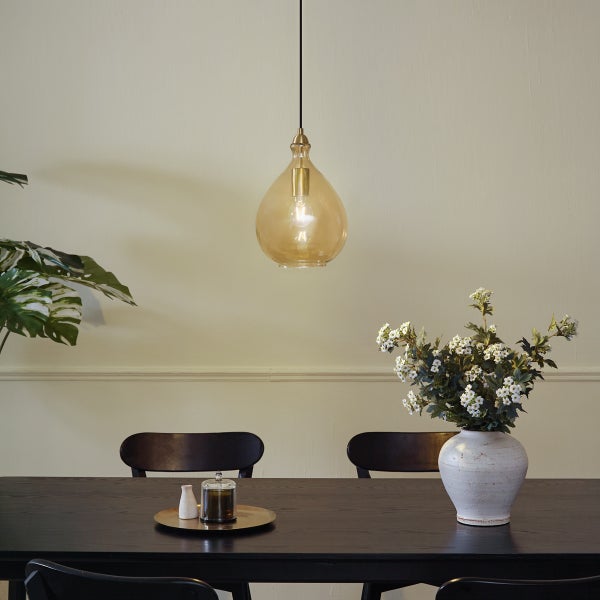 Esszimmer mit Esstisch, Stühlen, Blumenvase und einer bernsteinfarbenen Pendelleuchte