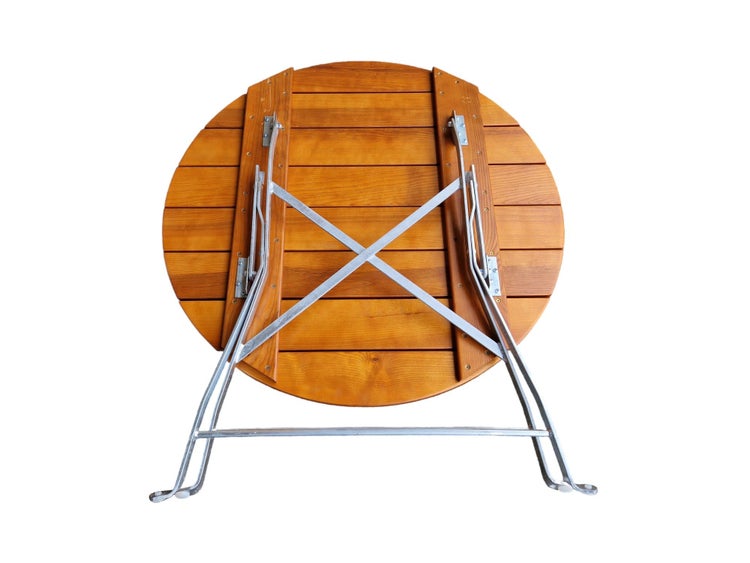 Klappbarer runder Gartentisch aus Holz mit verzinktem Metallgestell, Ansicht der Unterseite und Klappmechanismus.