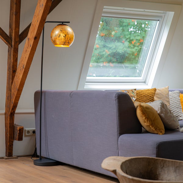 Wohnzimmer mit Deckenfenster, Holzbalken, Sofa und Stehlampe