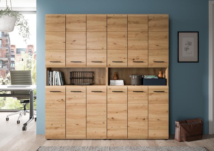 Großer Büroschrank aus Holz mit vielen Türen und offenem Regalfach in einem hellen, organisierten Homeoffice mit Fenster.