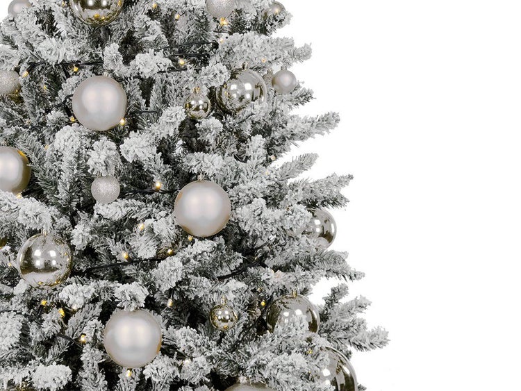 Künstlicher, verschneiter Weihnachtsbaum mit Lichterkette und glänzenden sowie matten Weihnachtskugeln als festliche Weihnachtsdekoration.