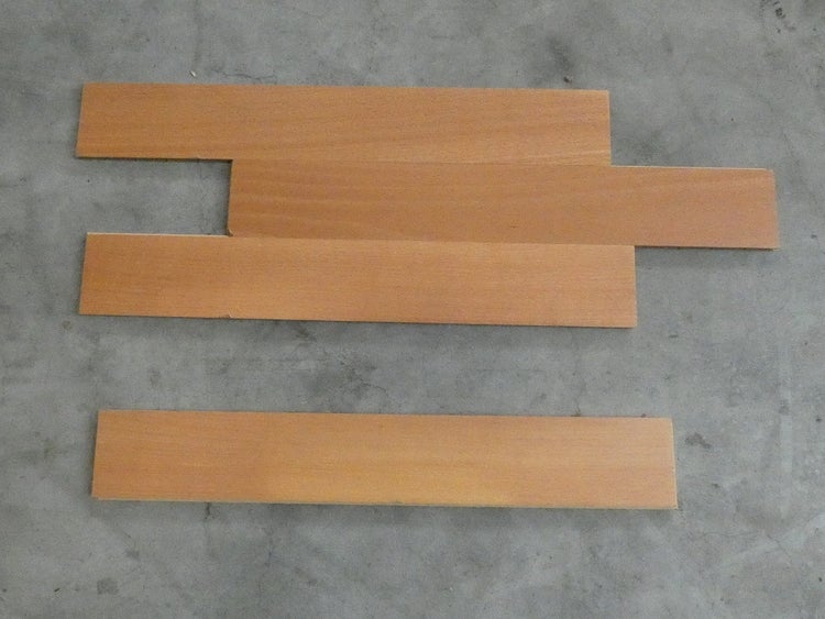 Vier Laminatpaneele in Holzoptik mit glatter Oberfläche, versetzt angeordnet.