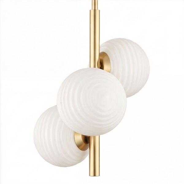 Moderne Hängeleuchte mit drei geriffelten weißen Glaskugeln an einer vertikalen goldfarbenen Metallstange.