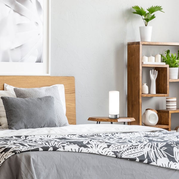 Schlafzimmer mit Holzbett, Nachttischlampe und Holzregal