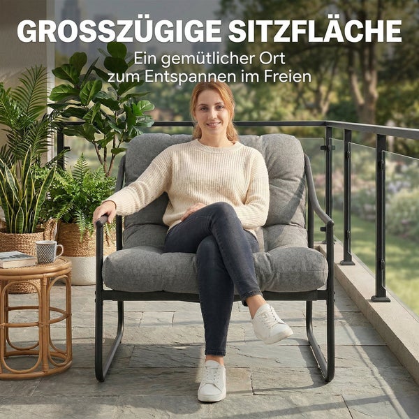 Frau in einem großzügigen Garten-Relaxsessel mit grauen Polstern und schwarzem Metallgestell auf einem Balkon mit Pflanzen.
