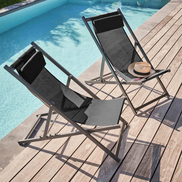Zwei klappbare Gartenliegen aus grauem Metall und schwarzem Textilgewebe auf einer Holzterrasse am Pool.