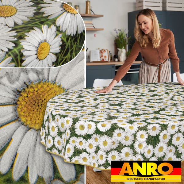 Frau deckt runden Tisch mit einer Tischdecke mit Gänseblümchenmuster.