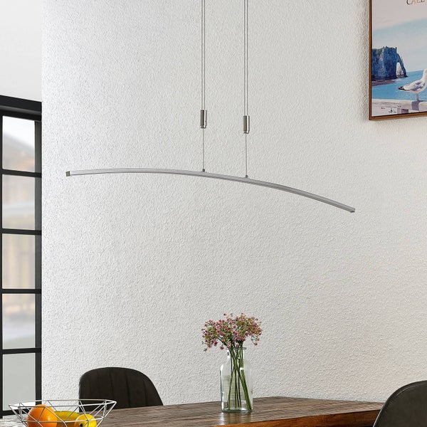 Moderne, gebogene LED-Pendelleuchte, höhenverstellbar, über einem Esstisch aus Holz in einem hellen Raum mit strukturierter Wand.