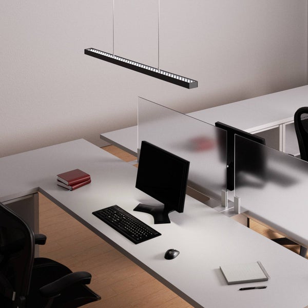 Moderne Büroumgebung mit langer schwarzer LED-Pendelleuchte über grauen Schreibtischen mit Computerarbeitsplätzen und Trennwänden aus Glas.