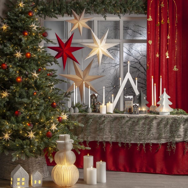 Weihnachtliche Dekoration mit Baum, Sternen, Lichtern, Kerzen und dekorativen Häusern für eine festliche Atmosphäre