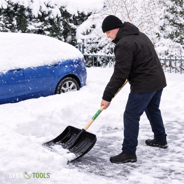 Mann schaufelt Schnee mit einer Schneeschaufel vor einem Auto