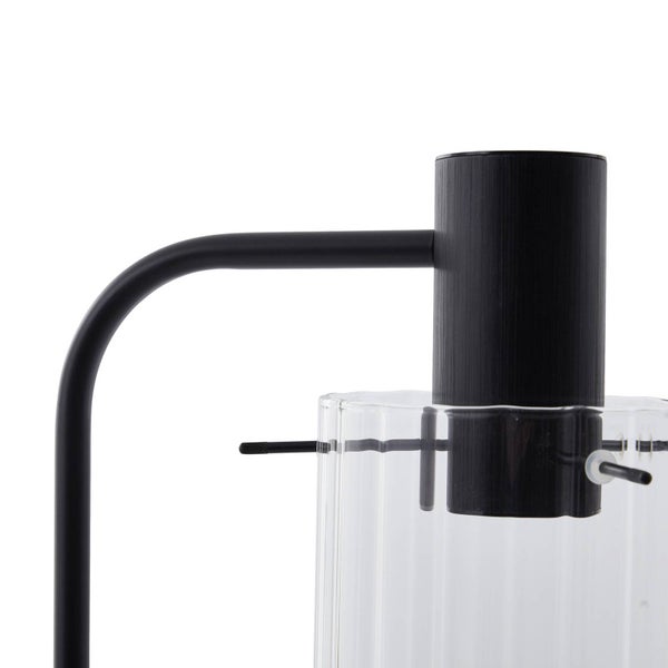 Nahaufnahme einer schwarzen Metalllampe mit zylindrischem Kopf und einem Lampenschirm aus geriffeltem Klarglas.