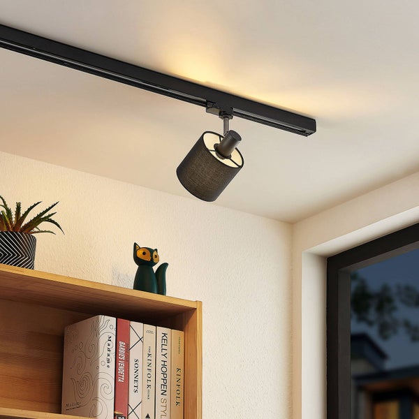 Schienensystem-Strahler mit schwarzem Textilschirm, montiert an einer schwarzen Schiene über einem Bücherregal.