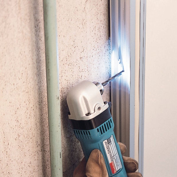 Makita Winkelbohrmaschine DA3010F beim Bohren in einen engen Spalt zwischen Wand und Rahmen mit LED-Licht.