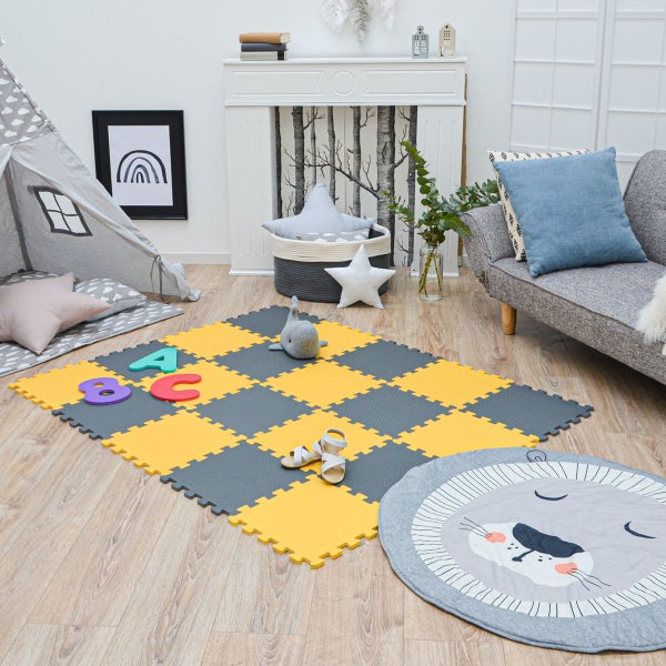 Helles Kinderzimmer mit gelb-grauer Puzzlematte aus Schaumstoff, grauem Tipi-Zelt, Sofa und rundem Löwen-Teppich auf Holzboden.