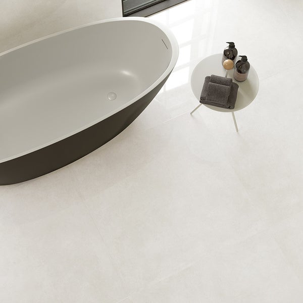 Modernes Badezimmer mit Badewanne und Bodenfliesen in Betonoptik.