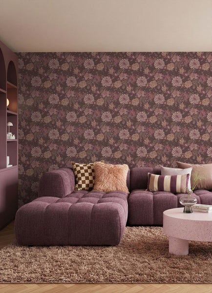 Wohnzimmer mit lilafarbenem Sofa, Couchtisch und floraler Tapete