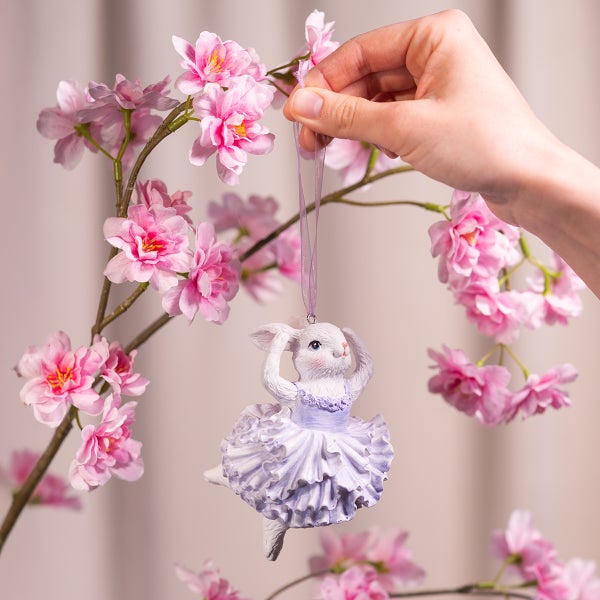 Dekorativer Hase als Ballerina mit Aufhänger vor blühendem Zweig