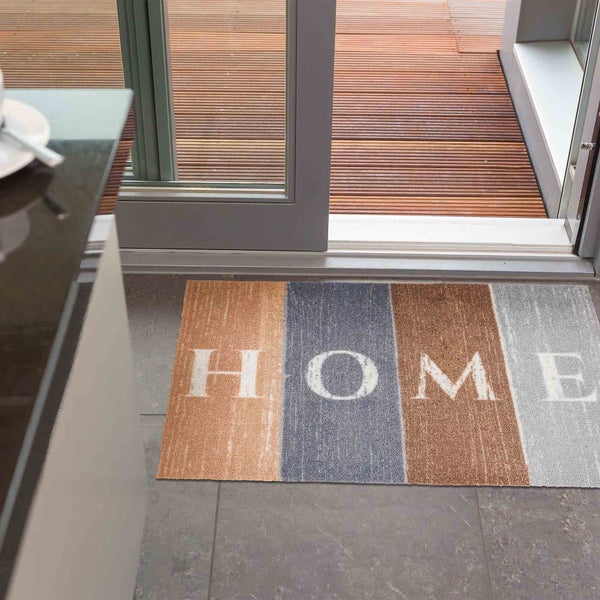 Fußmatte mit der Aufschrift HOME vor einer Terrassentür