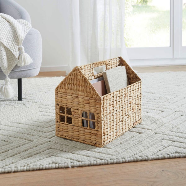 Dekorative Hausbox aus Wasserhyazinthe auf einem Teppich in einem Wohnzimmer.