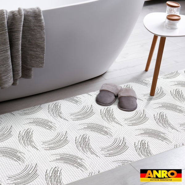 Badteppich mit abstraktem Linienmuster vor einer weißen Badewanne in einem hellen, organisierten Badezimmer. ANRO Logo.
