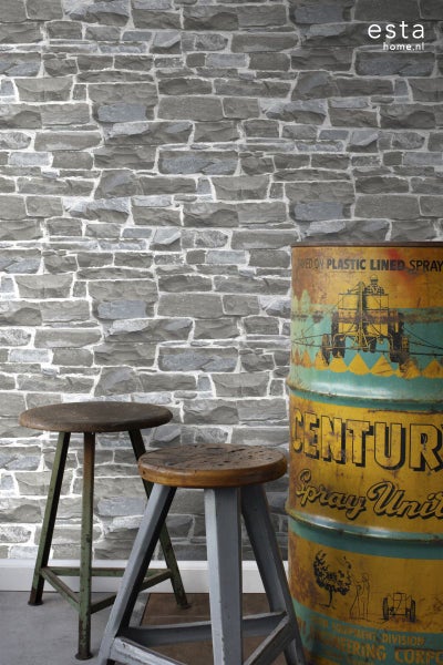 Wohnszene mit einer Backsteinmauer-Tapete, zwei Barhockern und einer Vintage-Öltonne