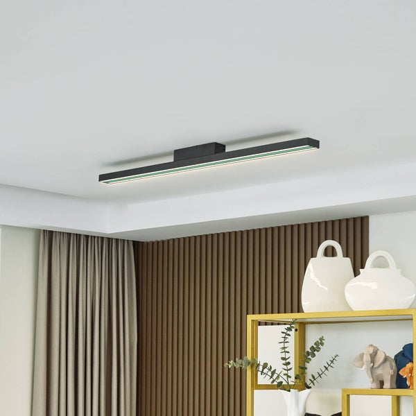 Moderne lineare LED-Deckenleuchte in einem hellen Raum mit vertikaler Holzpaneelwand, Vorhängen und einem Regal mit Dekorationsartikeln.