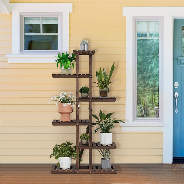 Pflanzenregal aus Holz mit verschiedenen Pflanzen im Topf vor Hauswand