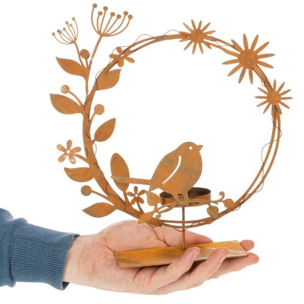 Deko-Aufsteller aus Metall in Rostoptik mit Vogel, Blumen und Blättern in Kranzform sowie einem Teelichthalter.